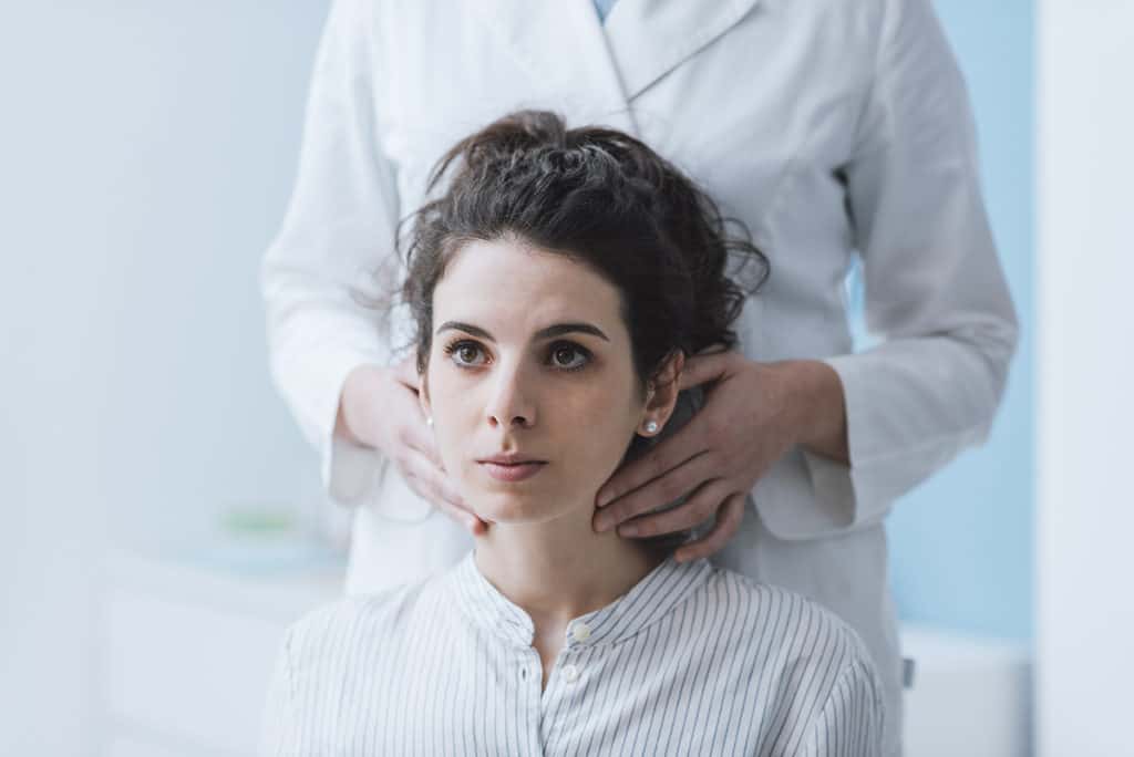 Woman having thyroid checked by doctor