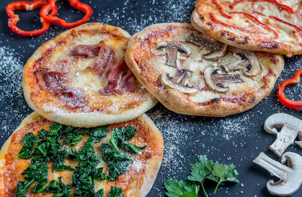 Mini pizzas with various toppings on the wooden board